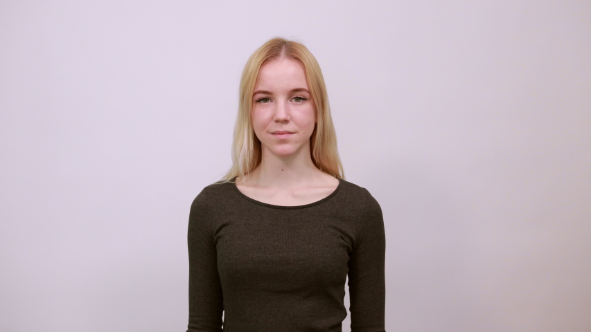Young Blonde Woman In Black Sweater With Stylish Watch On White Background, Silly Girl Having Fun, Holding Head With Hands, Sticking Out Her Tongue. The Concept Of Cheerful, Funny And Carefree People