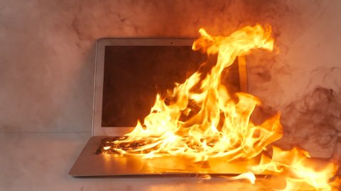 Burning laptop is hit with a strong gust, blowing bits of burned and blackened pieces away.