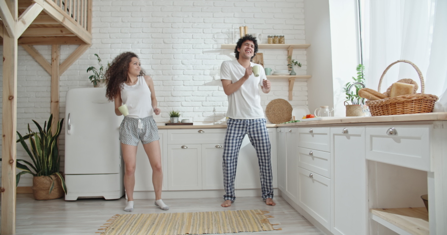 Cute asian couple in pajamas dancing while drinking their morning coffee and preparing for a new day, positively smiling - togetherness, love concept 4k Royalty-Free Stock Footage #1052577398