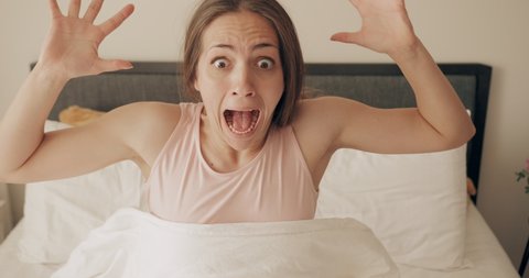 Young woman looking worried and stand up fast while oversleep. Panicing pretty girl realising late wake up for work while sleeping on bed. Concept of people and lifestyle