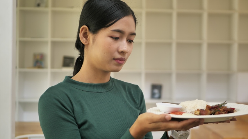 Slow motion young asian woman holding Crispy Pork Belly with basil and jasmine rice.
