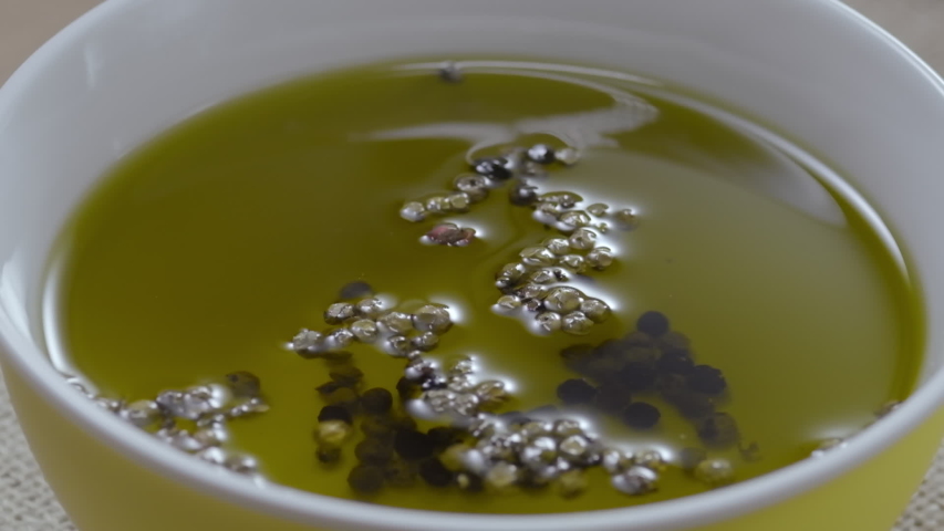 Red peppers drop into olive oil. Slow motion.