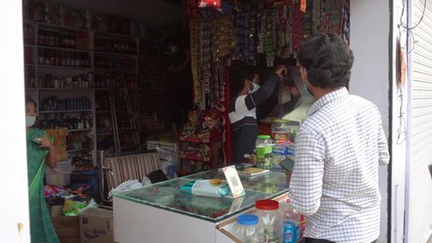Bharuch, Gujarat / India - May 07, 2020: Retailers and customers wearing a medical mask at grocery shop for prevention from COVID 19 Corona Virus. Customer doing digital payment. Lockdown 4 in India.