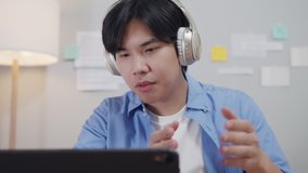 Attractive Asian Businessman or freelancer wears headphones having video call conference with colleagues talking, discussing, online business meeting remote working, and Distance job Work from home.