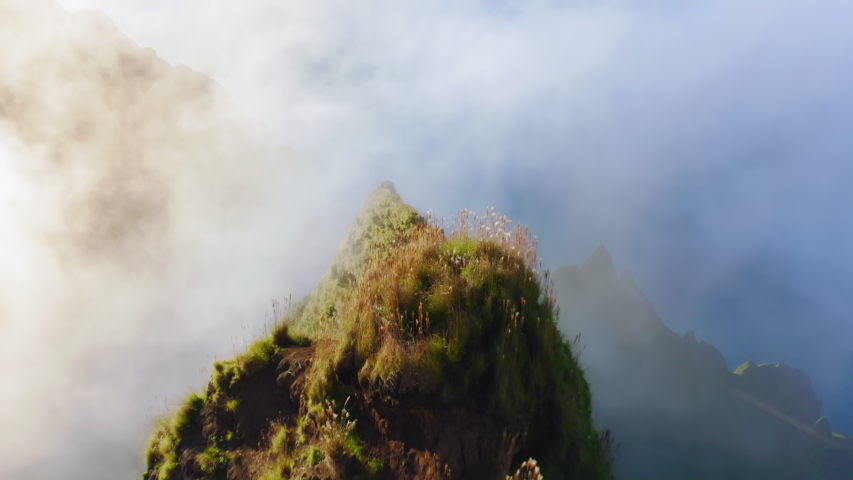 Na Pali Coast State park. Amazing Hawaii nature. Slow drone flight over the top of a narrow sharp mountain ridge with steep slopes, stretching forward towards the thick white cloud. Aerial, 4K