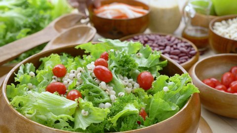 Hand woman chef Mixing Green Salad , Millet,Crab Stick, red tomato In glass bowl. Breakfast fresh salad and clean vegetable can eat raw. Nutritious and enzymes in Salad mix leaves green  can detox. 