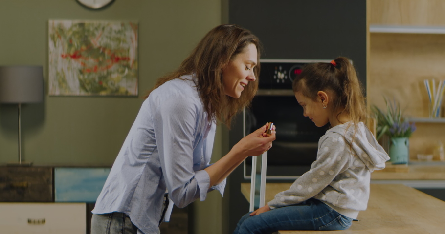 Mother playing with her daughter, applying lipstick. Stay home, quarantine life. Shot on RED Helium 8K