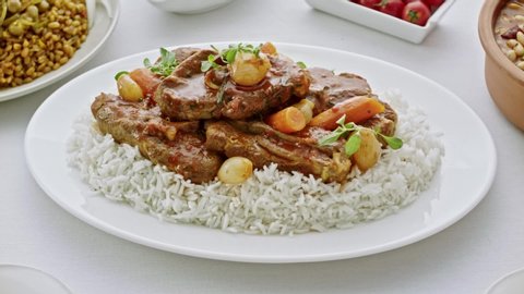 A plate of pilaf and pieces of meat. Pilaf and pieces of meat are put on the table with a large plate.