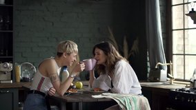 girl tastes tea in kitchen spbd. lesbian couple drink from mug. concept affectionate relationship. women preparing food. happy joyful gay friends enjoy beverage and discuss plans - Powered by Shutterstock - Get 15% off with code: PIKWIZARD15