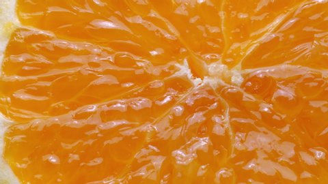 Squeezing a fresh and juicy orange. Extreme close up.