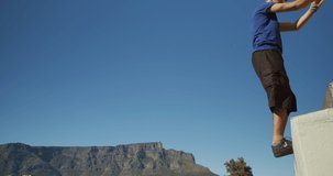 Caucasian man, wearing casual clothes, practicing parkour on a rooftop in a city on a sunny day, doing a somersault, in slow motion. - Powered by Shutterstock - Get 15% off with code: PIKWIZARD15