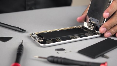 Locked down and close up of technician or engineer repairing or replace new parts of broken and damaged smartphone on desk. 4K resolution ultra HD