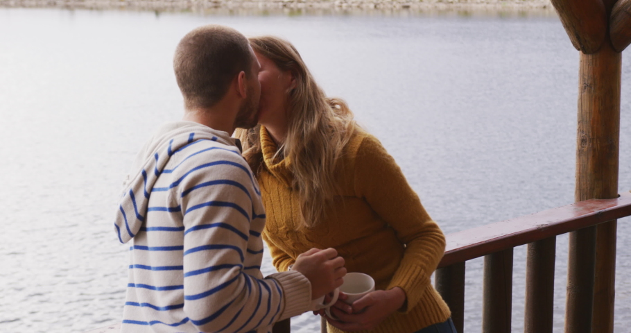 Caucasian couple spending time at home together, social distancing and self isolation in quarantine lockdown, standing outside their cabin, kissing in slow motion