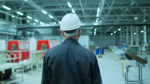 Follow footage of asian employees male warehouse worker engineer in hard hat working, walking through logistics center warehouse factory construction site architect businessman man indoors, slowmo 4 K