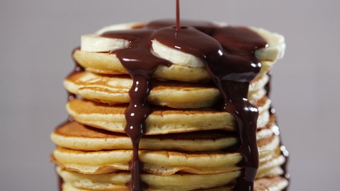 Pancakes with Chocolate Syrup, Nuts and Bananas. Stack of whole flapjack. Tasty breakfast and Healthy Food