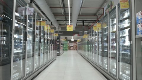 Frozen Food In Supermarket Aisle Tracking Shot. Tracking Shot of a big supermarket aisle with frozen food. People shopping in the background.