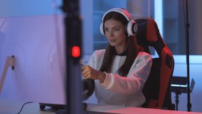 The young woman with headset plays video game with steering wheel