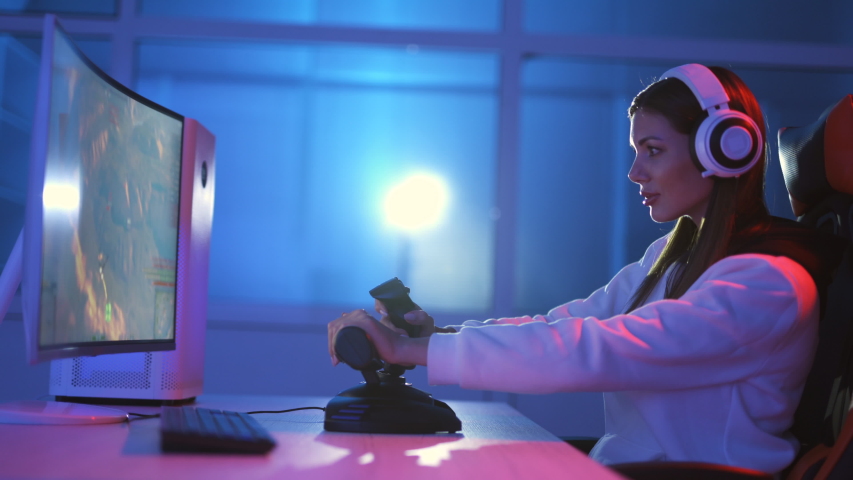 The attractive gamer girl with headphones plays video games