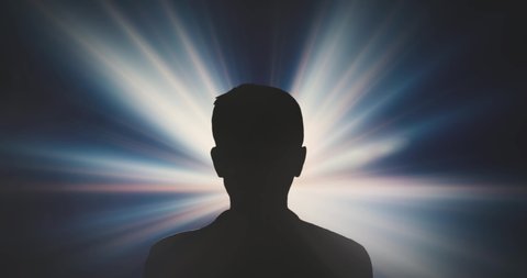 Silhouette of the back of a persons head against a glowing screen. Person looks in bright light. Light Rays in front of a dark person.の動画素材