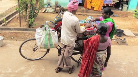 Yeleswaram , Andhra Pradesh / India - 11 02 2019: Indian village woman signs credit note for travelling turban-wearing sari salesman having bought a new sari from his bicycle stall, Yeleswaram, Andhra