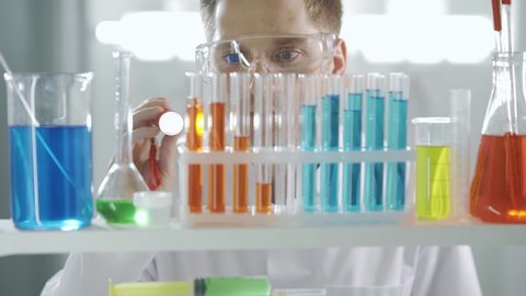Pharmaceutical research. Test-tubes with colored chemical reagents. A scientist examining a flask. Innovative pharmaceutical laboratory with medical equipment for genetics research. Chemistry.