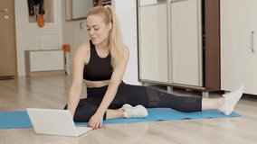Attractive young woman doing yoga stretching online at home. Self isolation entertainment and education on the Internet. Healthy lifestyle concept.
