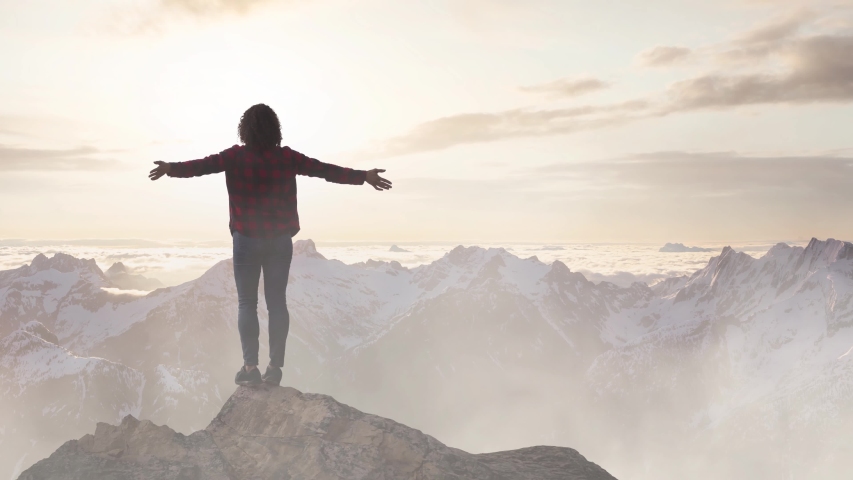 Fantasy Adventure Composite with a Girl on top of a Rock Cliff with Beautiful Canadian Mountain Nature Landscape in Background during Sunset or Sunrise. Parallax