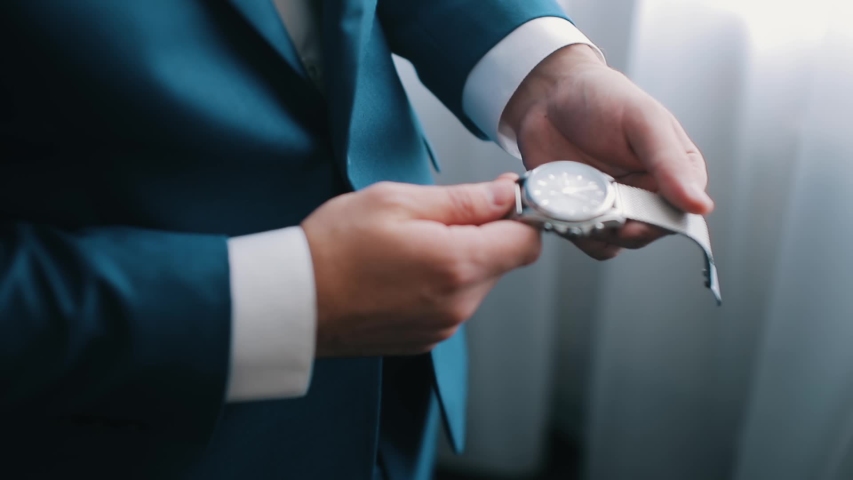 Business man puts on watch getting ready for work early in morning. Close-up of a successful man is putting on a watch. Men's hand with. Royalty-Free Stock Footage #1052678444