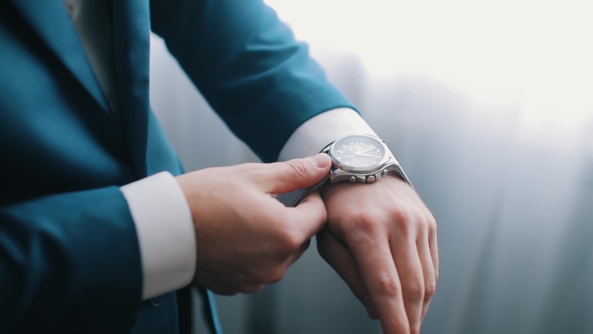 Business man puts on watch getting ready for work early in morning. Close-up of a successful man is putting on a watch. Men's hand with. Royalty-Free Stock Footage #1052678444