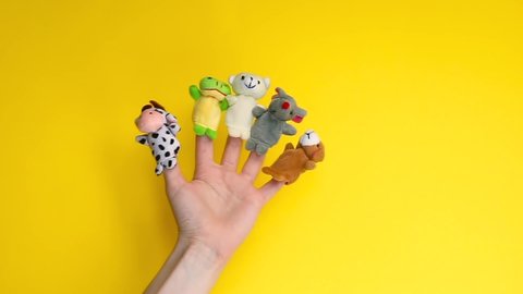 Puppet theater doll animals. Hand wearing finger puppets: cow, frog, dog, rabbit, mouse, bear. animal finger puppets show isolated on yellow background. family quarantine fun. template mock up.