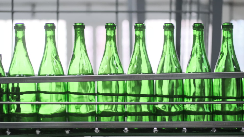 Wine bottles moving along a conveyor belt in a wine bottling factory. Manufacture of wine bottle. Glass recycling. Bottle manufacturing industrial factory. sparkle and still wines . prores HQ Royalty-Free Stock Footage #1052681552
