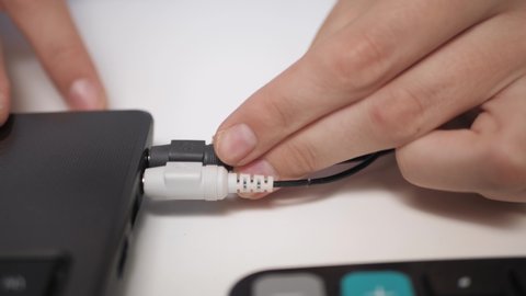 Female hand includes plug from headphone and microphone into laptop