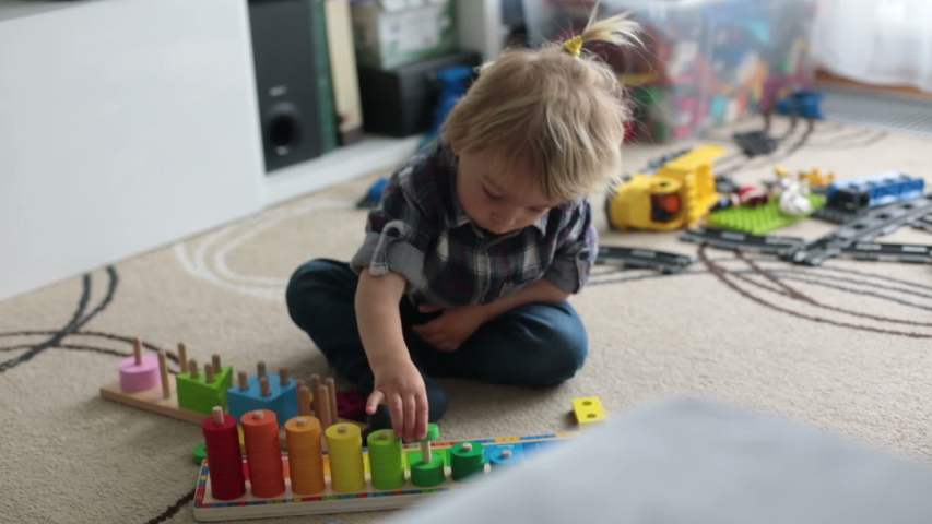 Little blonde toddler child,  boy playing with wooden toys developing and learning activities