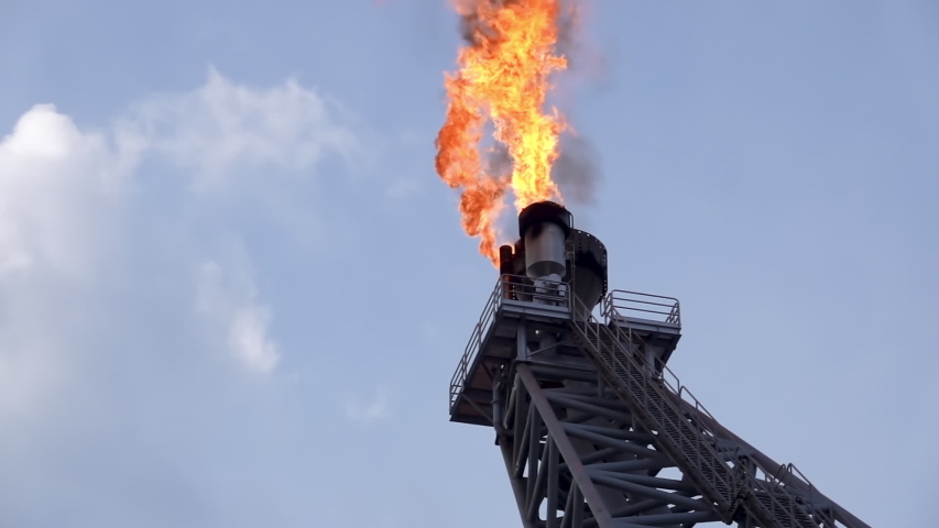 Oil and gas. Slow motion of gas flare from bottom burning at oil and gas platform with background blue sky and clouds. Royalty-Free Stock Footage #1052689685