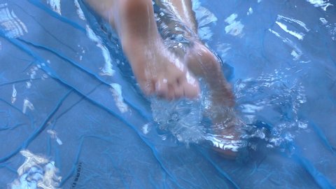 Using feet for swimming inside the pool and waves with water and movement.