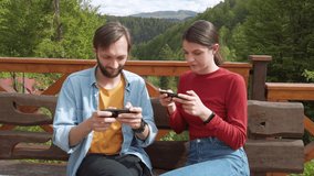 Couple playing game on mobile phone. Girl wins a guy a game on a mobile phone. Celebrating a win. Mountains on background.