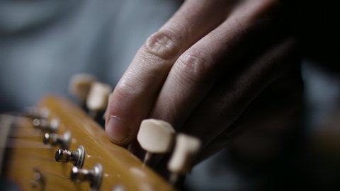 A musician tunes a guitar for a performance. Playing music instrument. Shot on RED camera in 4k.