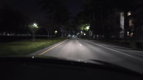 Empty roadway with luminous lampposts and illuminated buildings on the sides on the night sky background in Miami in the USA. Video recording from the moving car.