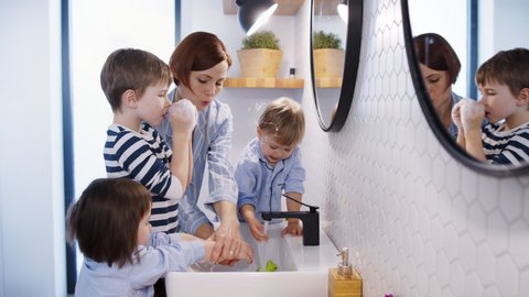 Mother with small children in pajamas in bathroom at home, washing hands.