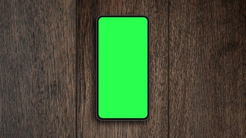 Top view, Smart phone place on table wood with green screen, Close-up the cell phone is on the brown desktop with chroma key, Green screen telephone, slider and top view.