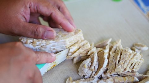 person is cutting tempeh for the fried tempeh