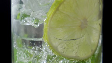 Close-up refreshing soda tonic. Pour carbonated water into a glass of lime and ice. Cold Mojito lemonade