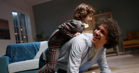 Young asian father playing with his little son. Funny kid with curly hair doing a piggy back ride, having fun at home - happy family, recreational pursuit concept 4k footage