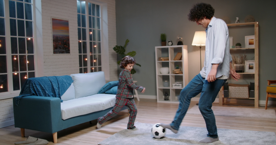 Young asian father and his son with curly hair playing football. Funny man dribbling the ball, enjoying his time together with kid - happy family, recreational pursuit concept 4k footage | Shutterstock HD Video #1052706755
