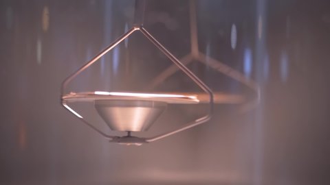 Super slow motion: hanging metal gyroscope spinning top pendulum - interactive exposition at science exhibition museum - close up. Physics, experiment, education, laboratory equipment concept