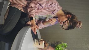 Vertical video of attractive woman with glasses typing on digital tablet on kitchen