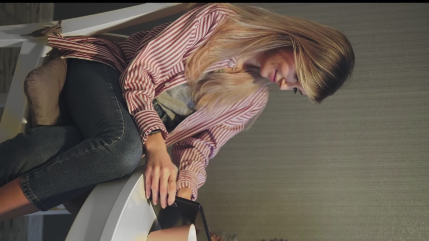 Vertical video of attractive woman watching a video on digital tablet on kitchen