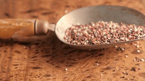 Black raw quinoa in old metal spoon rotating, South American grain. Healthy and gluten free food concept background.