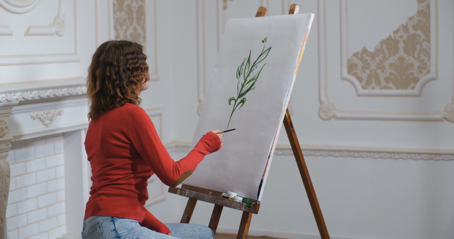 Art therapy for fire survivor. Young attractive woman with burn scars on face painting on canvas on easel in white classic interior. Breaking female body beauty standards. Inclusiveness concept