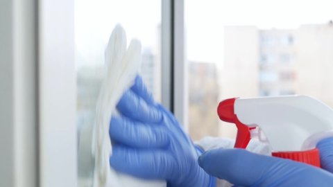 Slow Motion Man Hands with Blue Gloves Cleaning a Window Using Sprayed Liquid Disinfecting Against COVID-19 Contamination